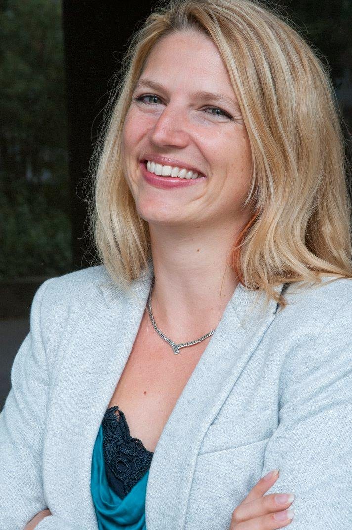 Nathalie Sameli lächelt im hellen Blazer mit verschränkten Armen