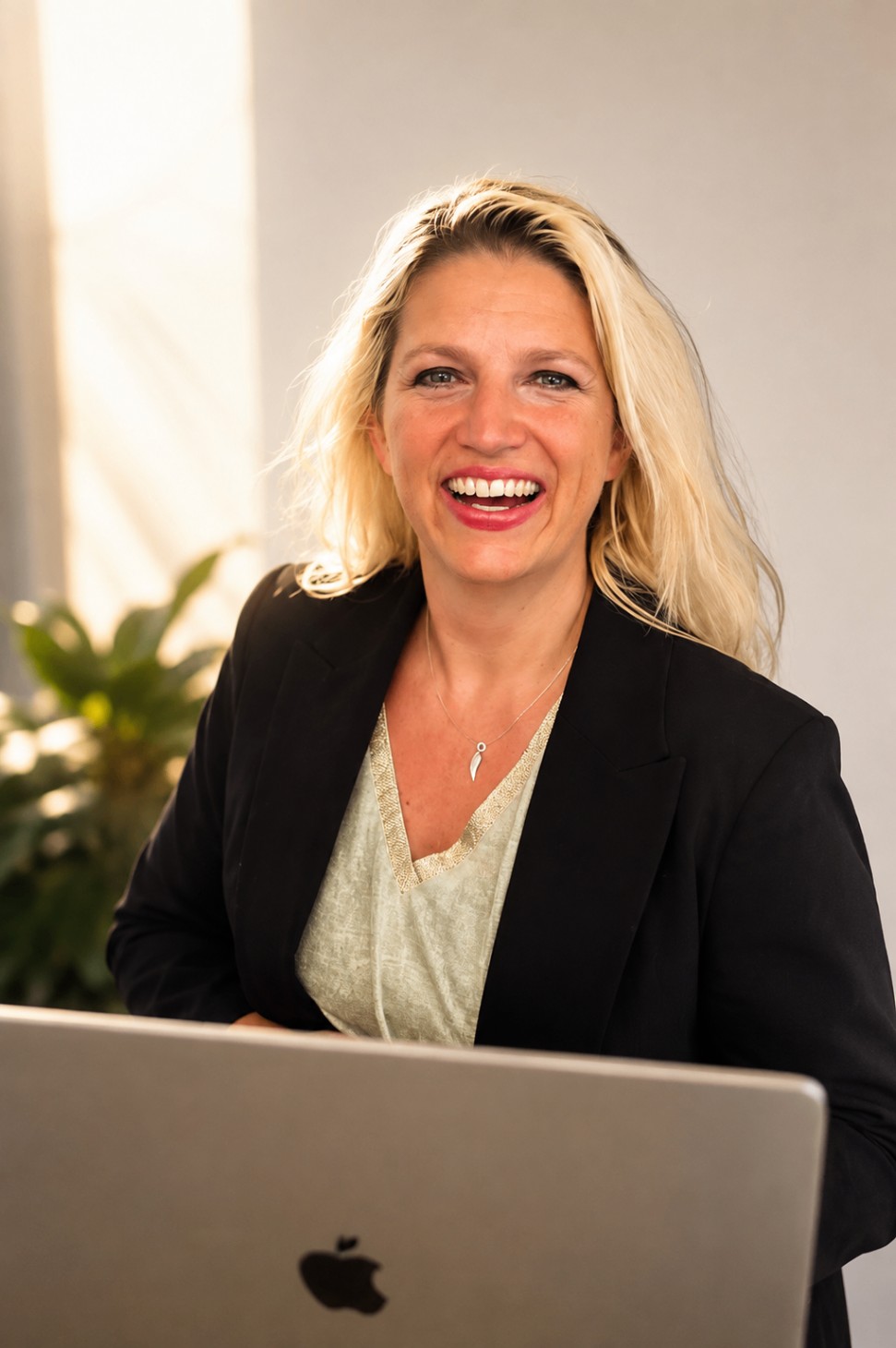 Nathalie Sameli lacht am Laptop in einem hellen Raum