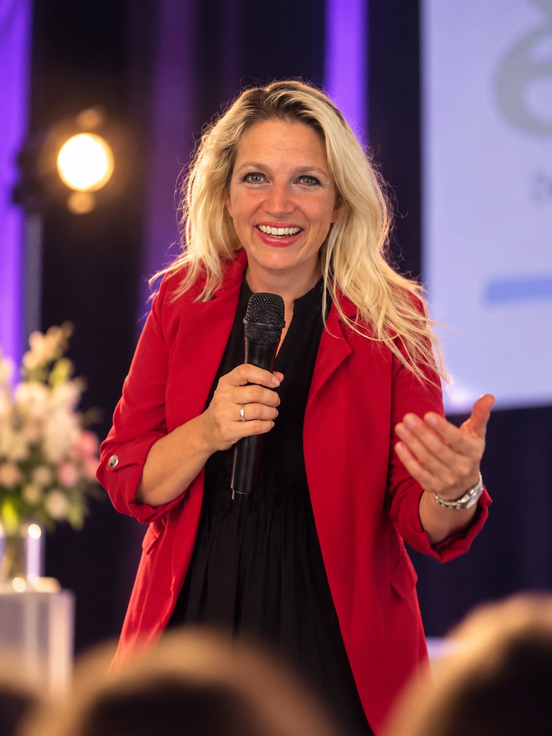 Nathalie Sameli im roten Blazer bei einem Bühnenvortrag