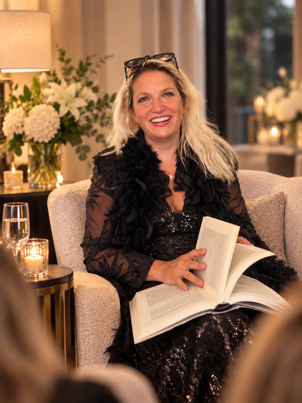Nathalie Sameli sitzt lächelnd in einem Sessel mit einem offenen Buch